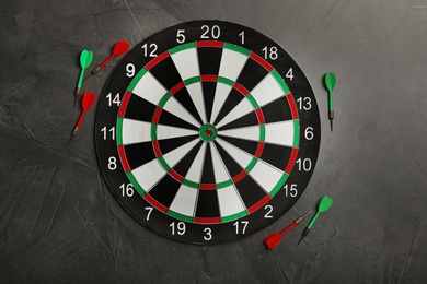 Photo of Dart board with color arrows on grey stone background, top view