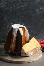 Delicious Pandoro cake with powdered sugar and Christmas decor on grey table