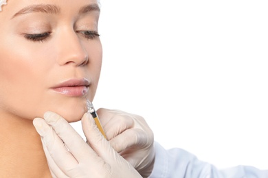 Young woman getting lips injection on white background, closeup. Cosmetic surgery