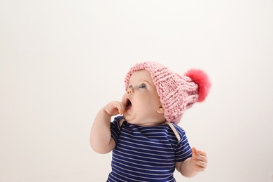 Little child in knitted hat on light background. Baby accessories