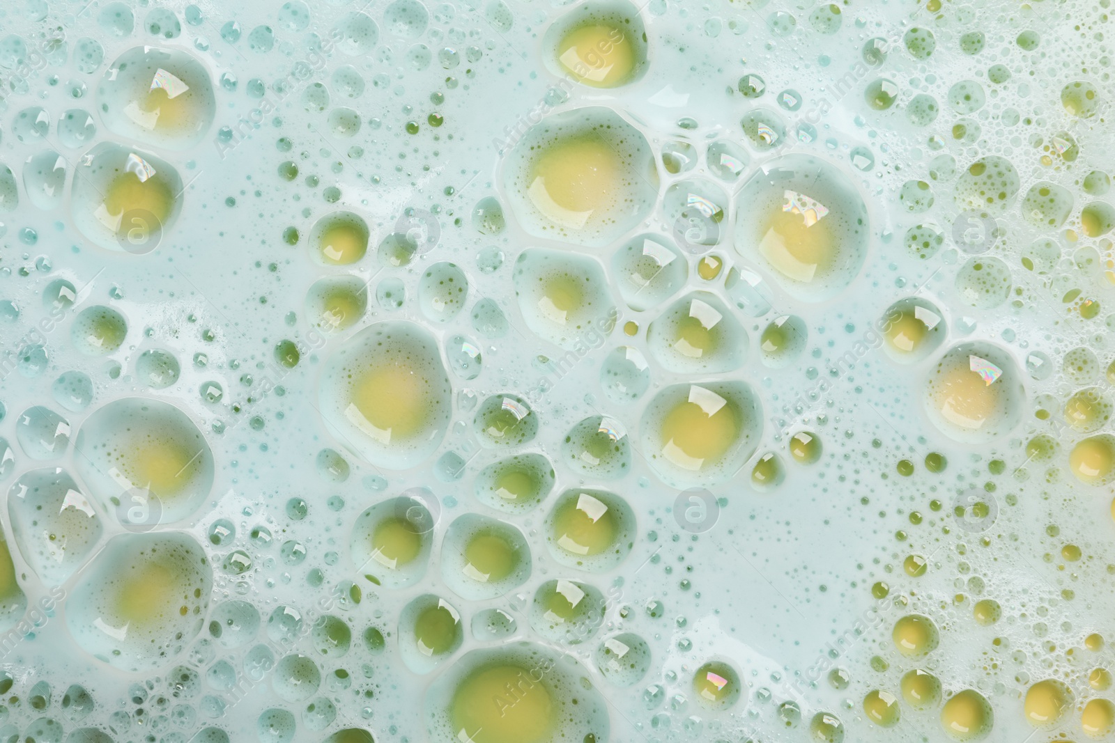 Photo of Color washing foam on yellow background, top view