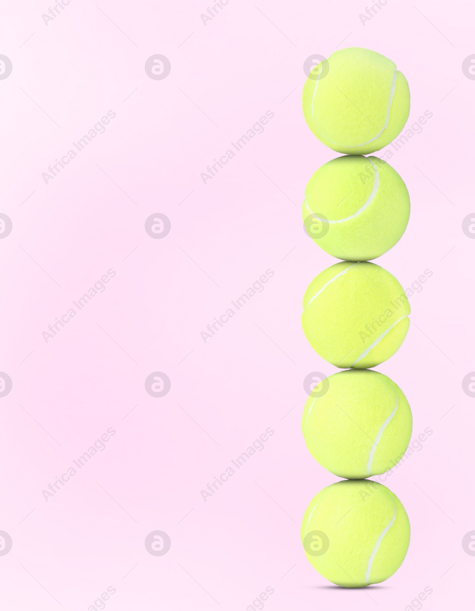 Image of Stack of tennis balls on pale pink background. Space for text