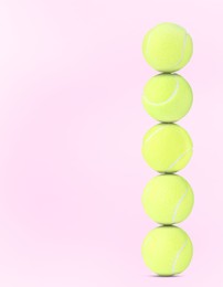 Image of Stack of tennis balls on pale pink background. Space for text