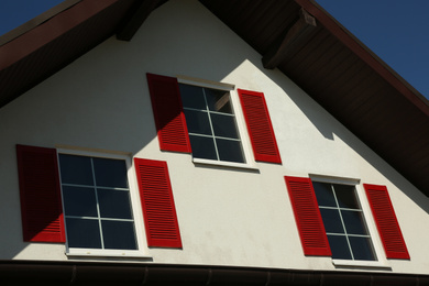 Photo of Beautiful building with windows and red shutters on sunny day