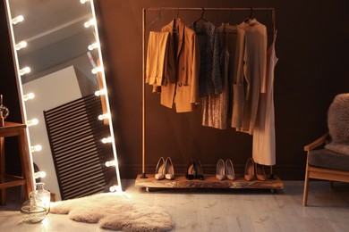 Stylish mirror with light bulbs and comfortable armchair in dressing room. Interior design