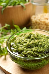 Photo of Bowl of tasty arugula pesto on table, closeup