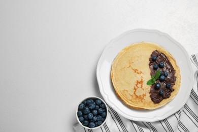 Photo of Delicious crepes with fresh berries and chocolate on white table, flat lay. Space for text