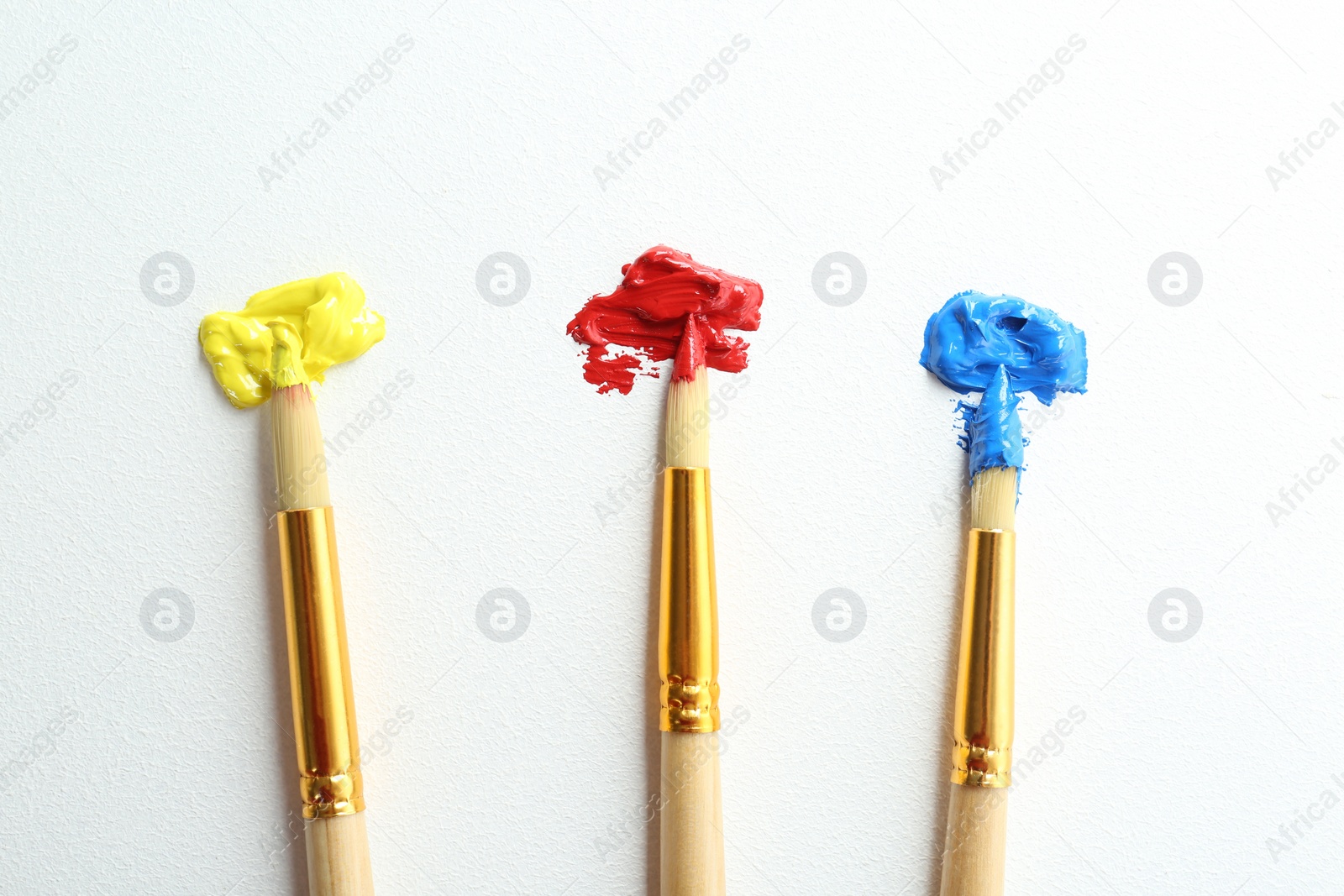 Photo of Brushes with bright paints on white background, top view