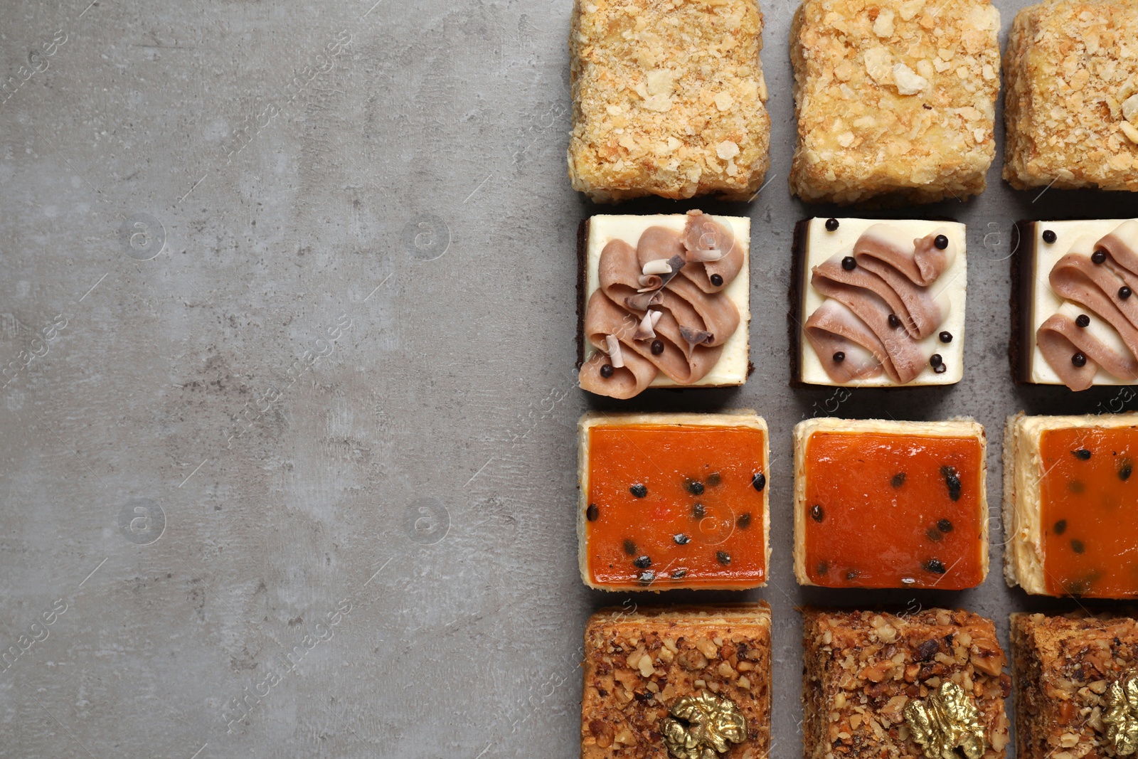 Photo of Pieces of different delicious cakes on grey table, flat lay. Space for text