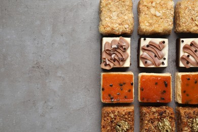 Photo of Pieces of different delicious cakes on grey table, flat lay. Space for text
