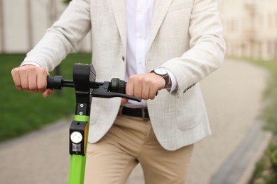 Businessman with modern kick scooter on city street, closeup