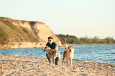 Young man walking his adorable Akita Inu dogs near river