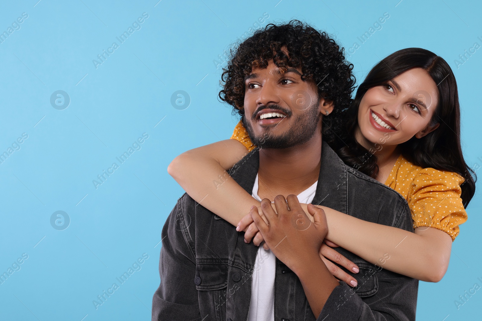 Photo of International dating. Happy couple hugging on light blue background, space for text