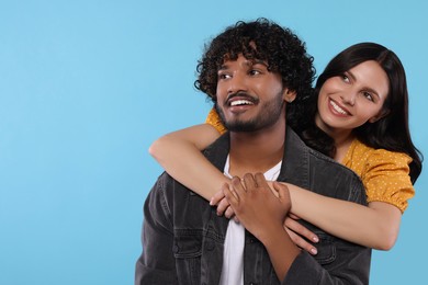 Photo of International dating. Happy couple hugging on light blue background, space for text