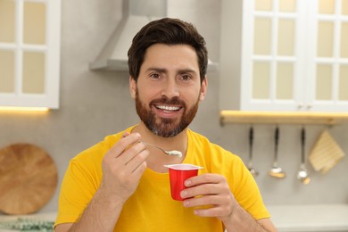 Photo of Handsome man with delicious yogurt in kitchen