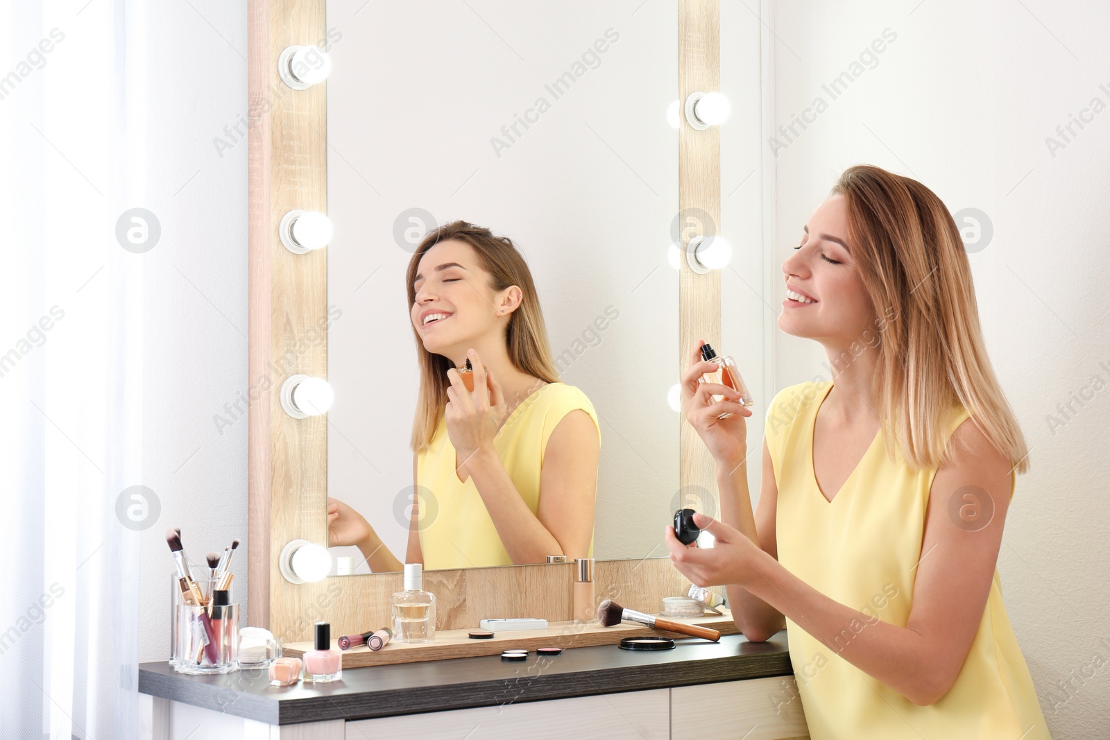 Photo of Woman applying perfume near mirror in dressing room