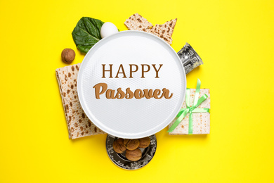 Image of Symbolic Passover items on yellow background, flat lay. Pesah celebration