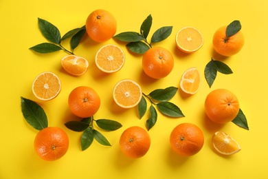 Fresh ripe oranges with green leaves on yellow background, flat lay