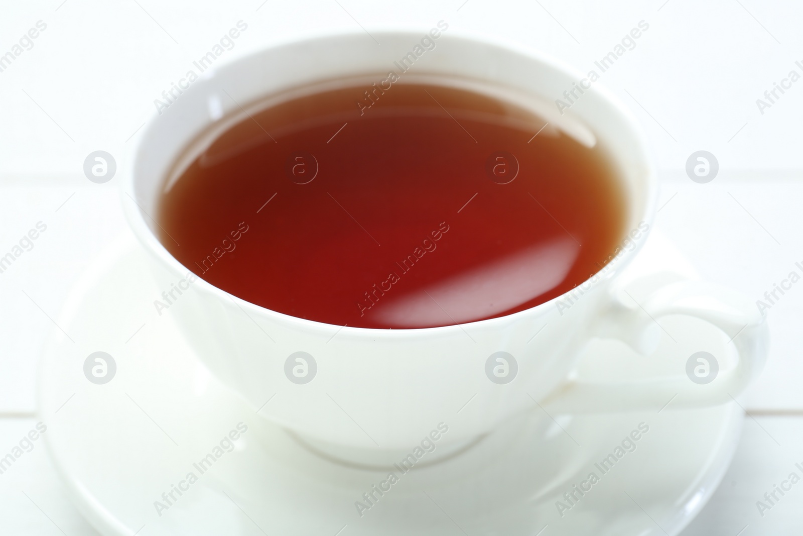 Photo of Aromatic tea in cup on white table, closeup