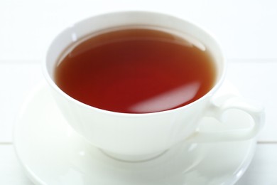 Photo of Aromatic tea in cup on white table, closeup