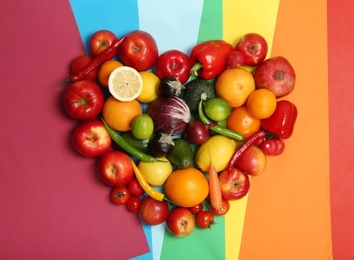 Photo of Rainbow heart made of fruits and vegetables on color background