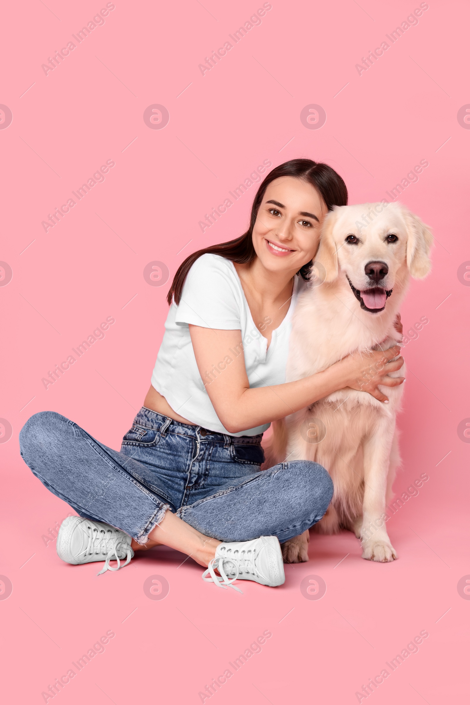 Photo of Happy woman with cute Labrador Retriever dog on pink background. Adorable pet