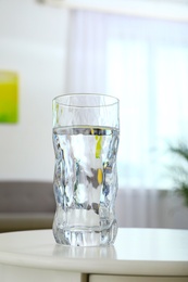 Photo of Glass of water on table in room. Refreshing drink