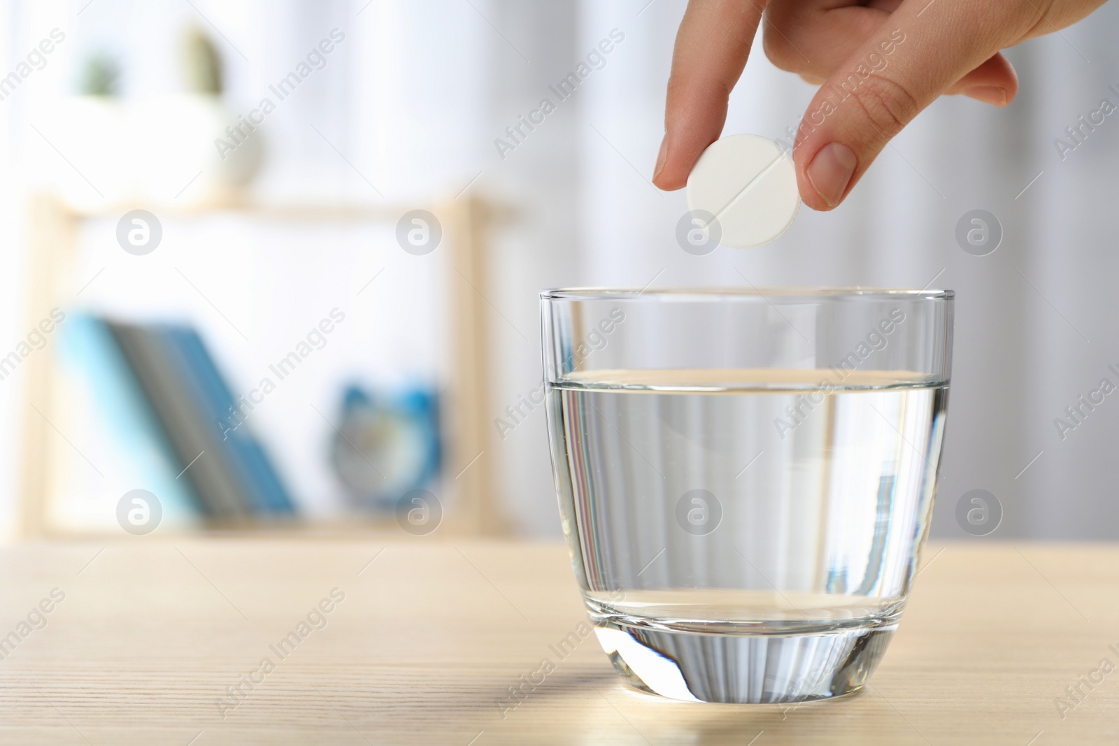 Photo of Woman putting tablet into glass of water indoors, space for text