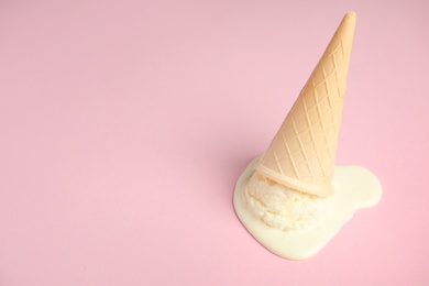 Photo of Melted  vanilla ice cream in wafer cone on pink background. Space for text