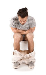 Young man suffering from diarrhea on toilet bowl. Isolated on white