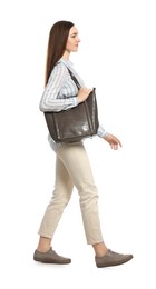 Young woman with stylish bag walking on white background