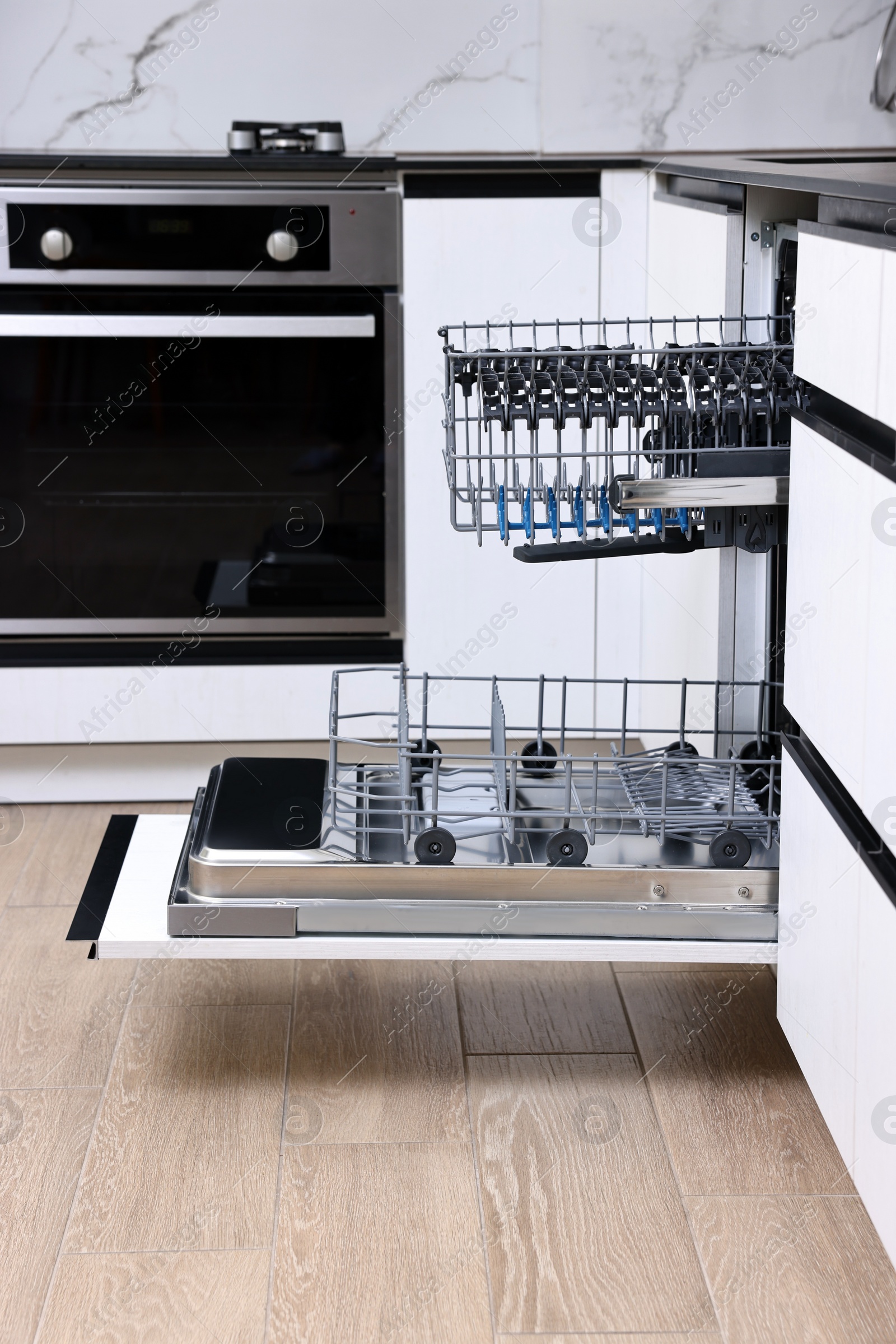 Photo of Open clean empty dishwasher in kitchen. Home appliance