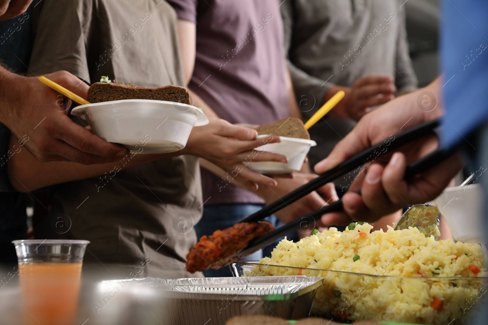 Photo of Volunteer serving food to poor people in charity centre, closeup