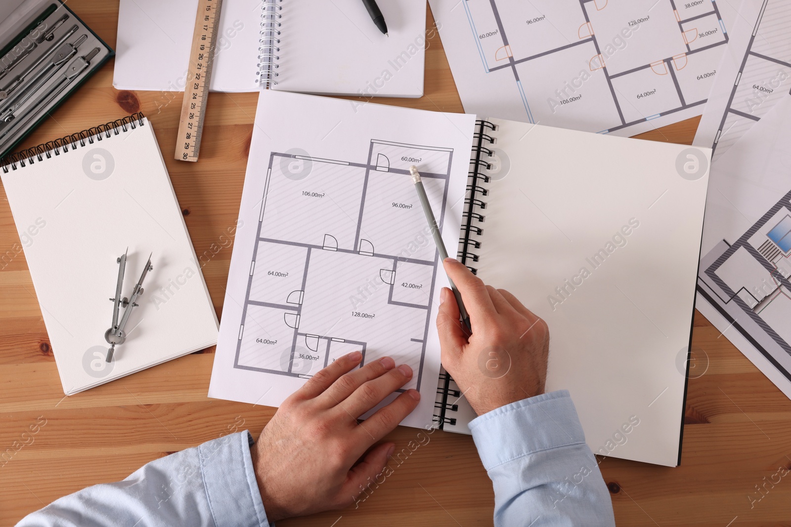 Photo of Man with sketchbook and pencil at wooden table, top view