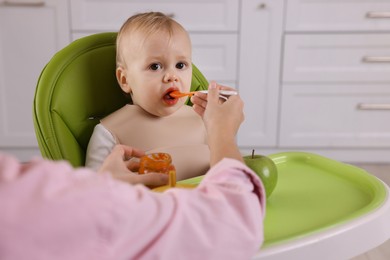Photo of Mother feeding her cute little baby with healthy food at home