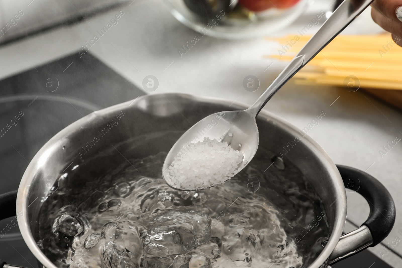 Photo of Salting boiling water in pot on stove, closeup