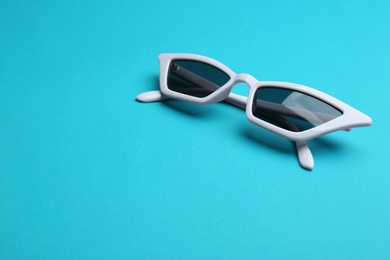 Photo of Stylish sunglasses on blue background, space for text. Fashionable accessory