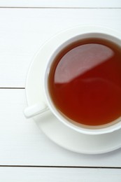 Photo of Aromatic tea in cup on white wooden table, top view