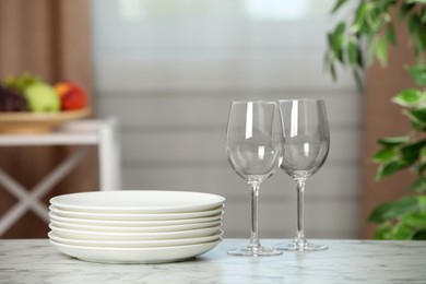 Stack of plates and glasses on white marble table indoors