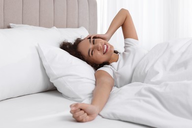 Photo of Happy African American woman awakening in bed at home