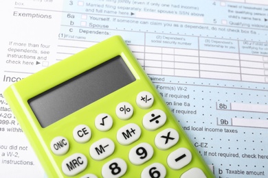 Photo of Green calculator on document, closeup view. Tax accounting