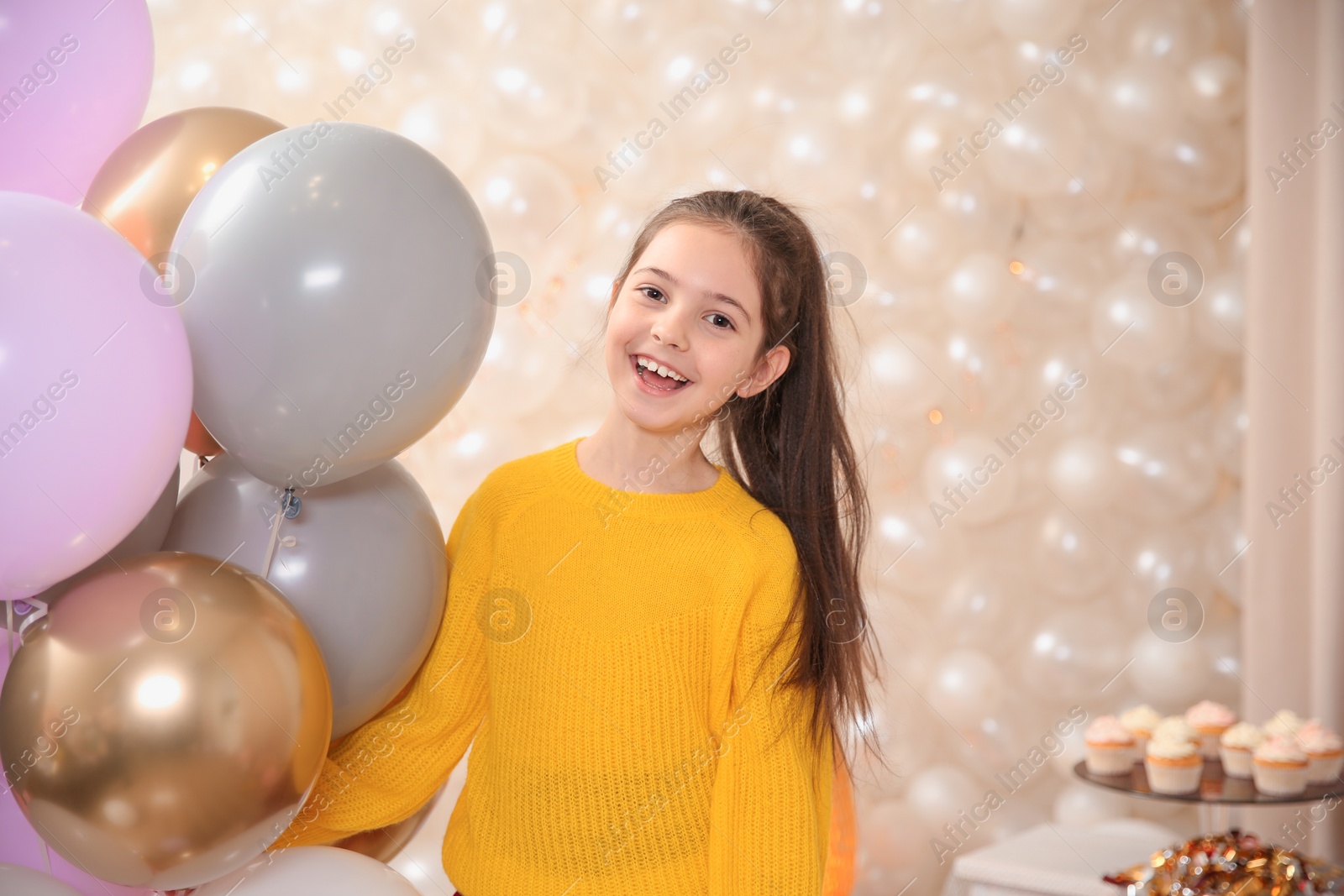 Photo of Happy little girl with balloons in beautifully decorated room at home. Birthday celebration