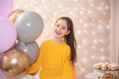 Happy little girl with balloons in beautifully decorated room at home. Birthday celebration