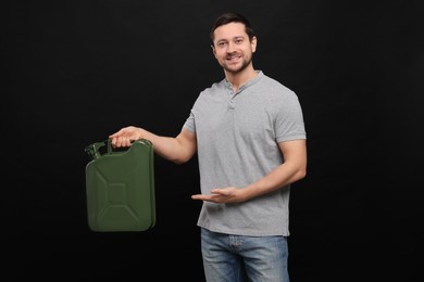 Photo of Handsome man showing khaki metal canister on black background