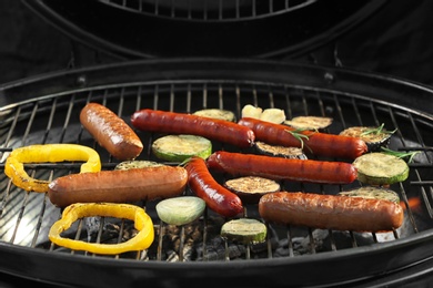 Photo of New modern barbecue grill with tasty sausages and vegetables, closeup