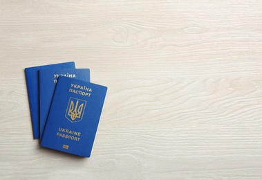 Ukrainian travel passports on wooden background, top view with space for text. International relationships