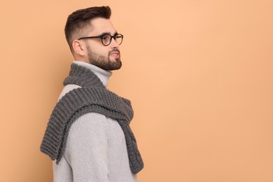 Photo of Handsome man in knitted scarf on beige background. Space for text