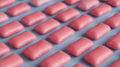 Photo of Many sweet chewing gums on light blue background, closeup