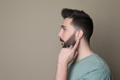 Photo of Man pointing at his ear on grey background. Space for text