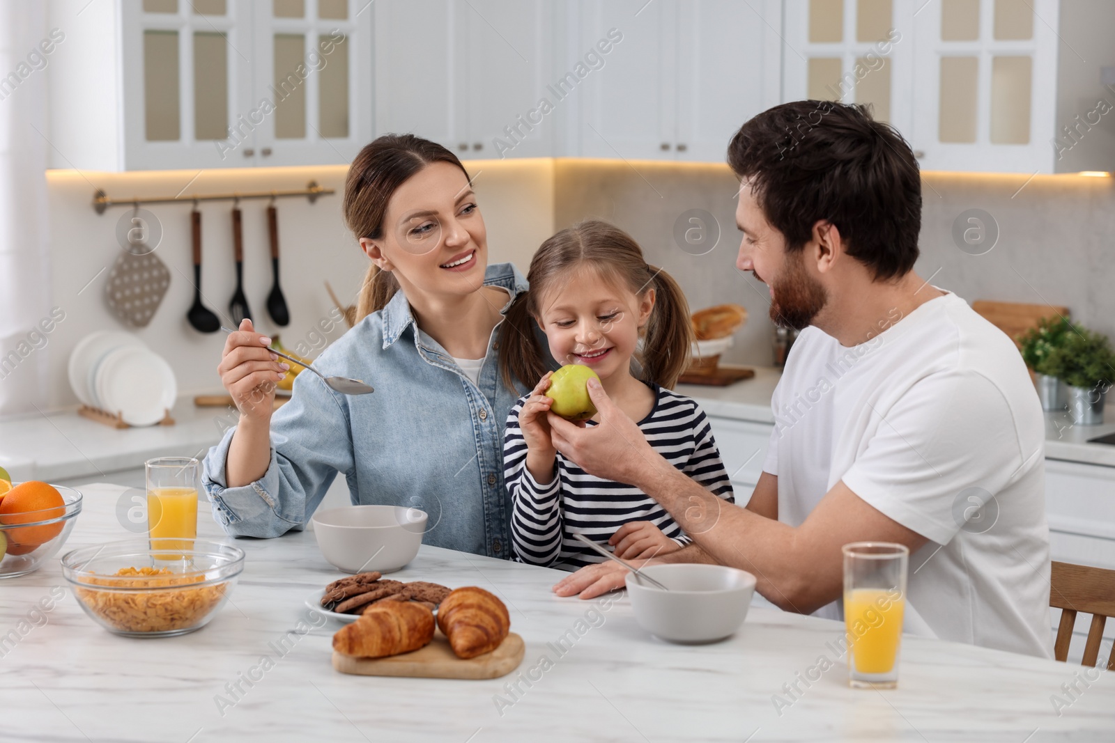 Photo of Happy family having breakfast at table in kitchen